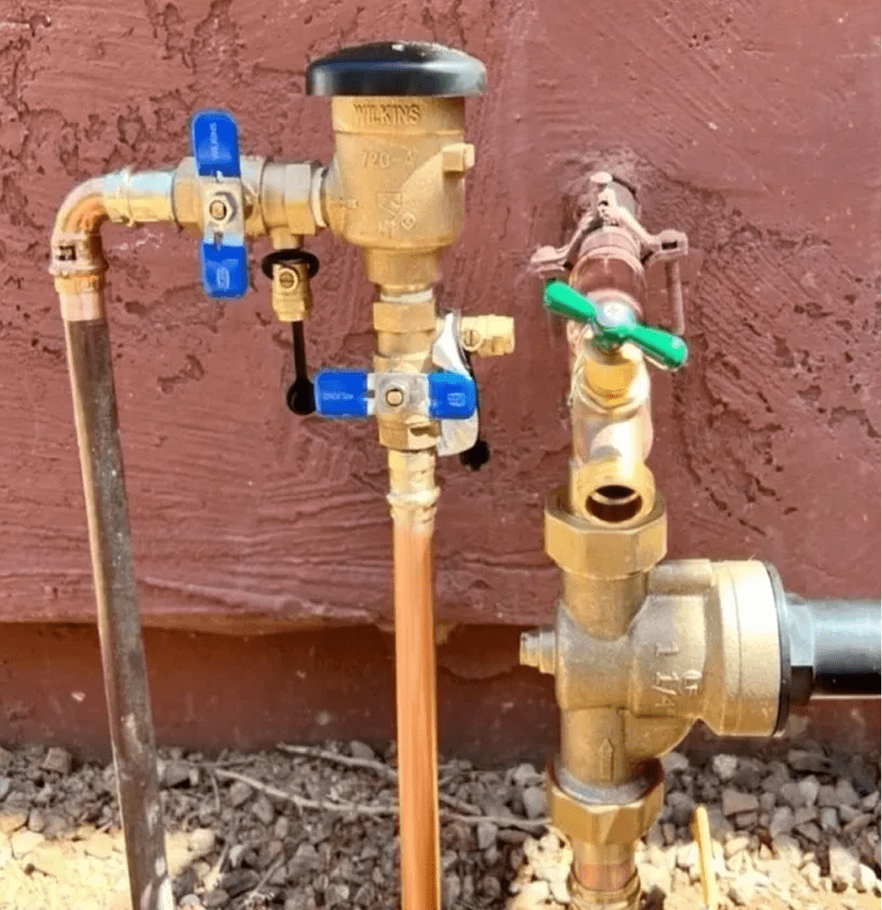 Outdoor plumbing pipes with valves and connectors.