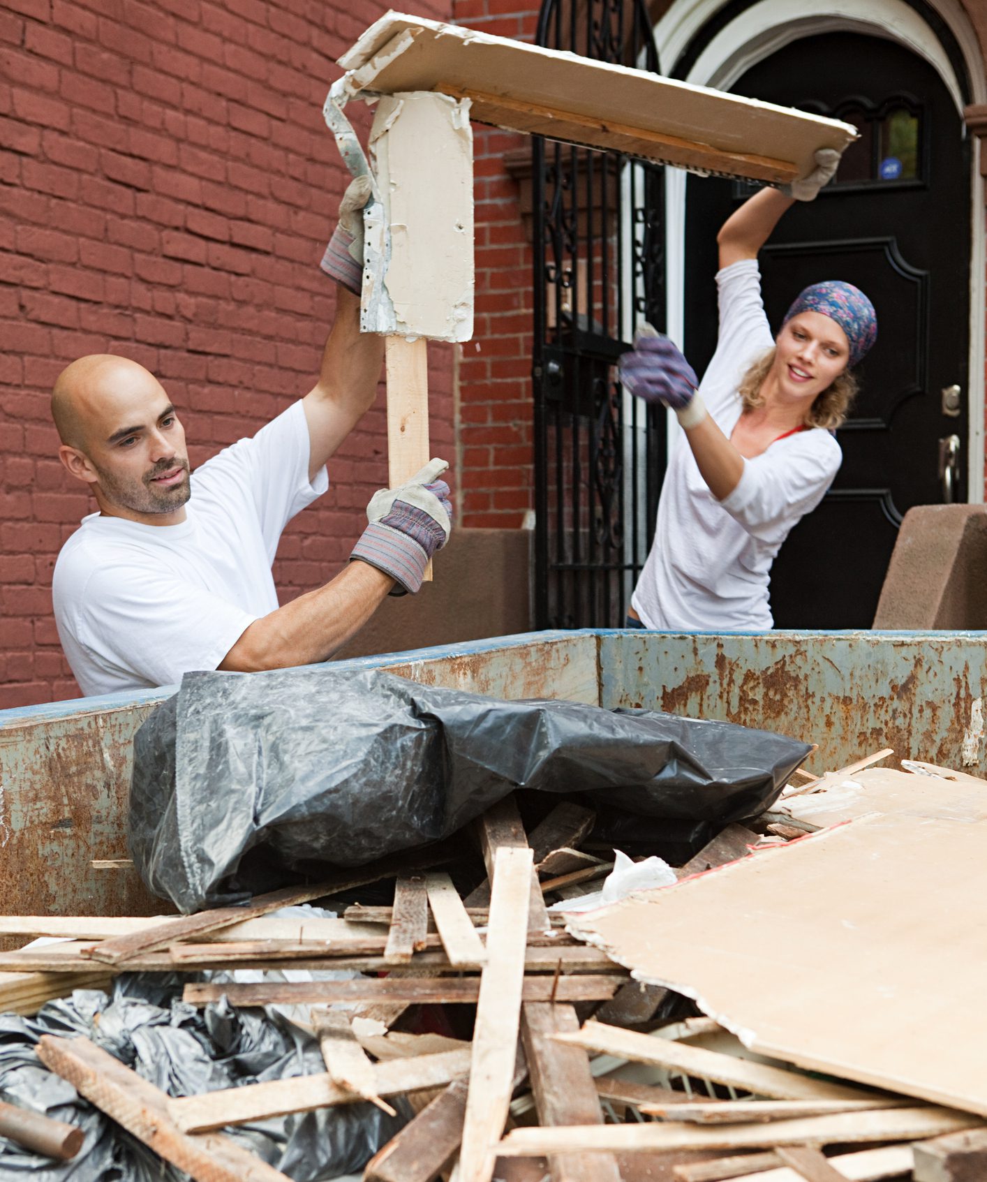 Couple filling skip with rubble