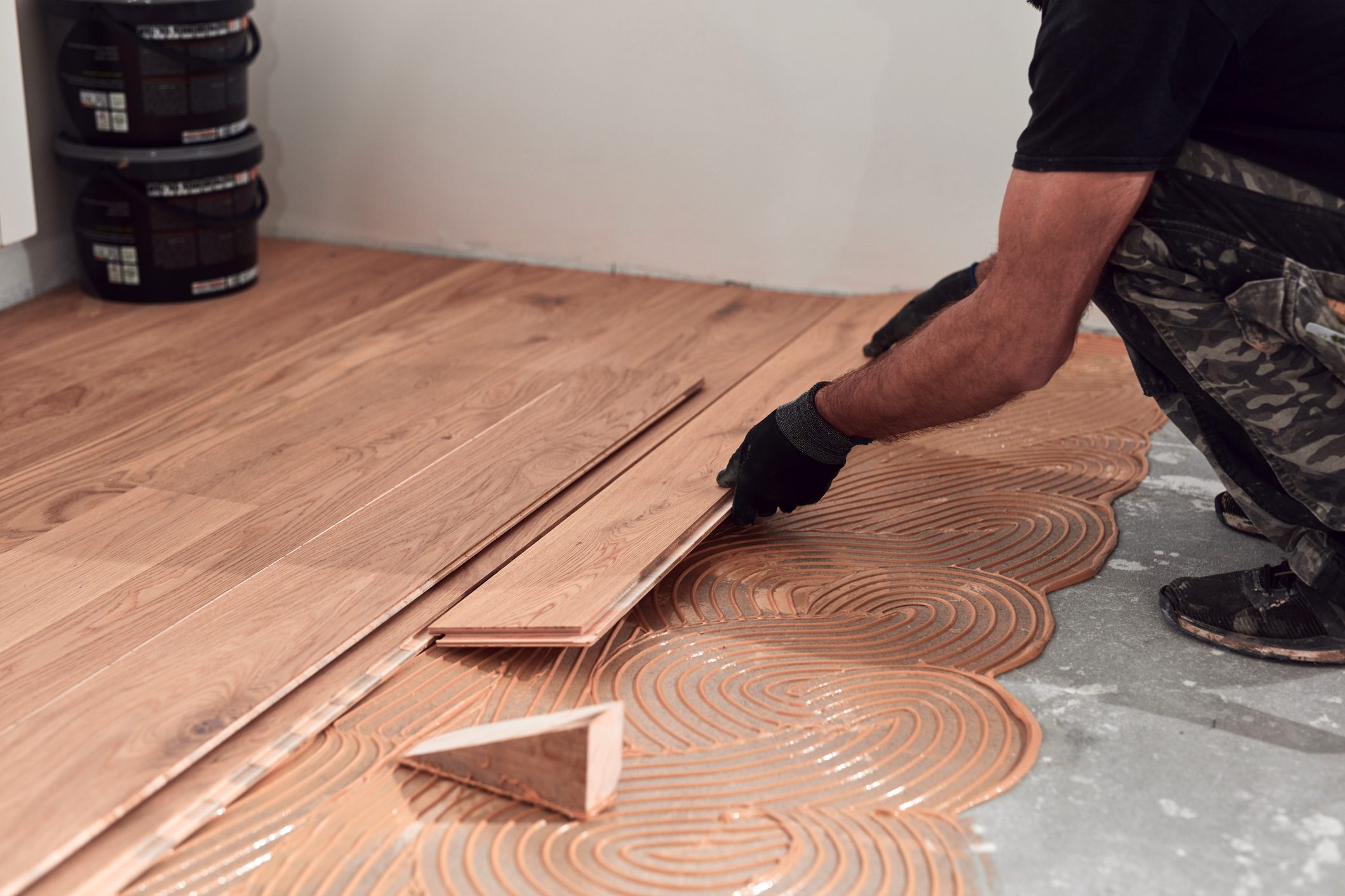 Professional handyman installing laminate flooring in a new apartment.