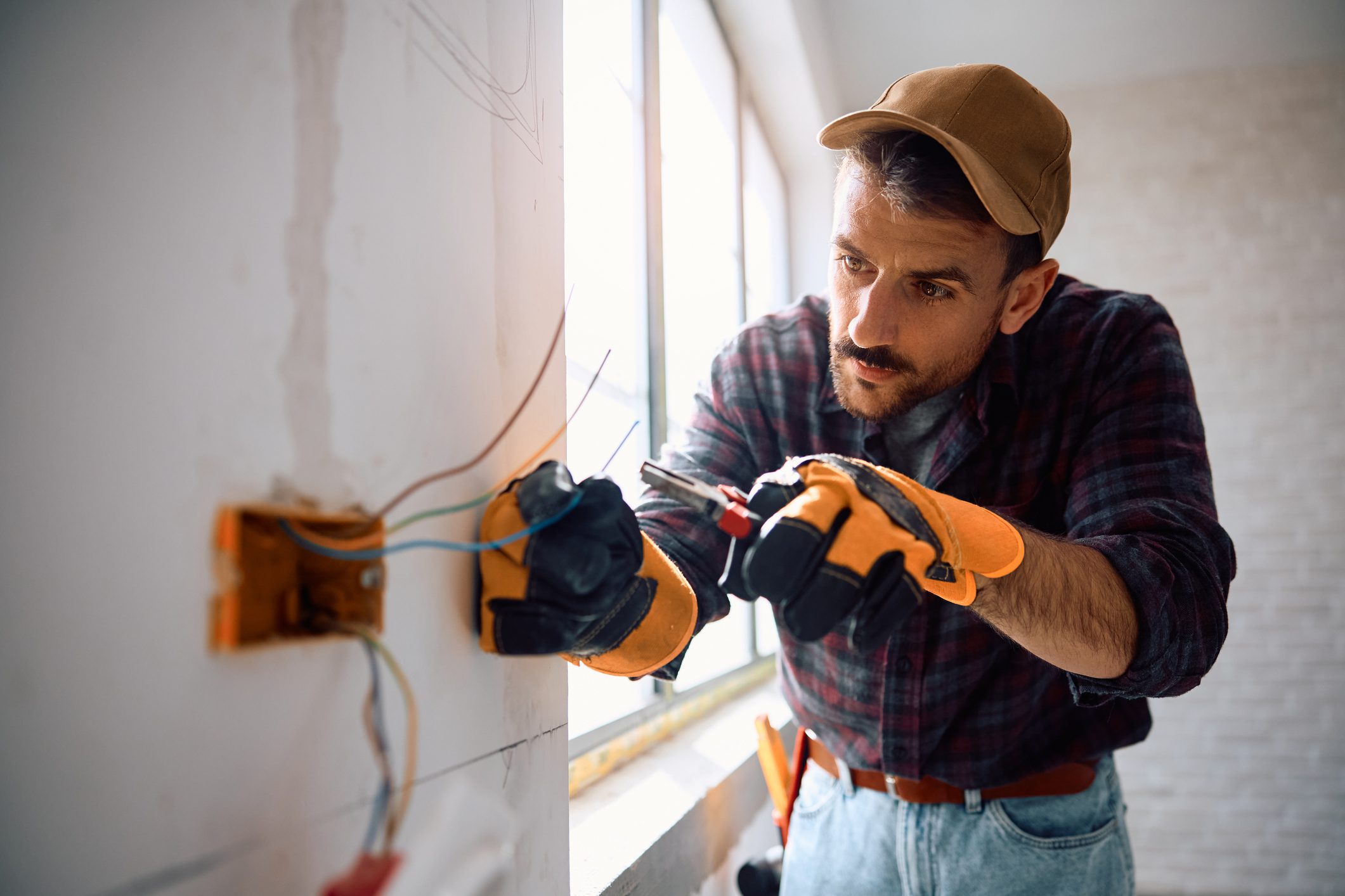 Manual worker installing electric cables at construction site. Copy space.