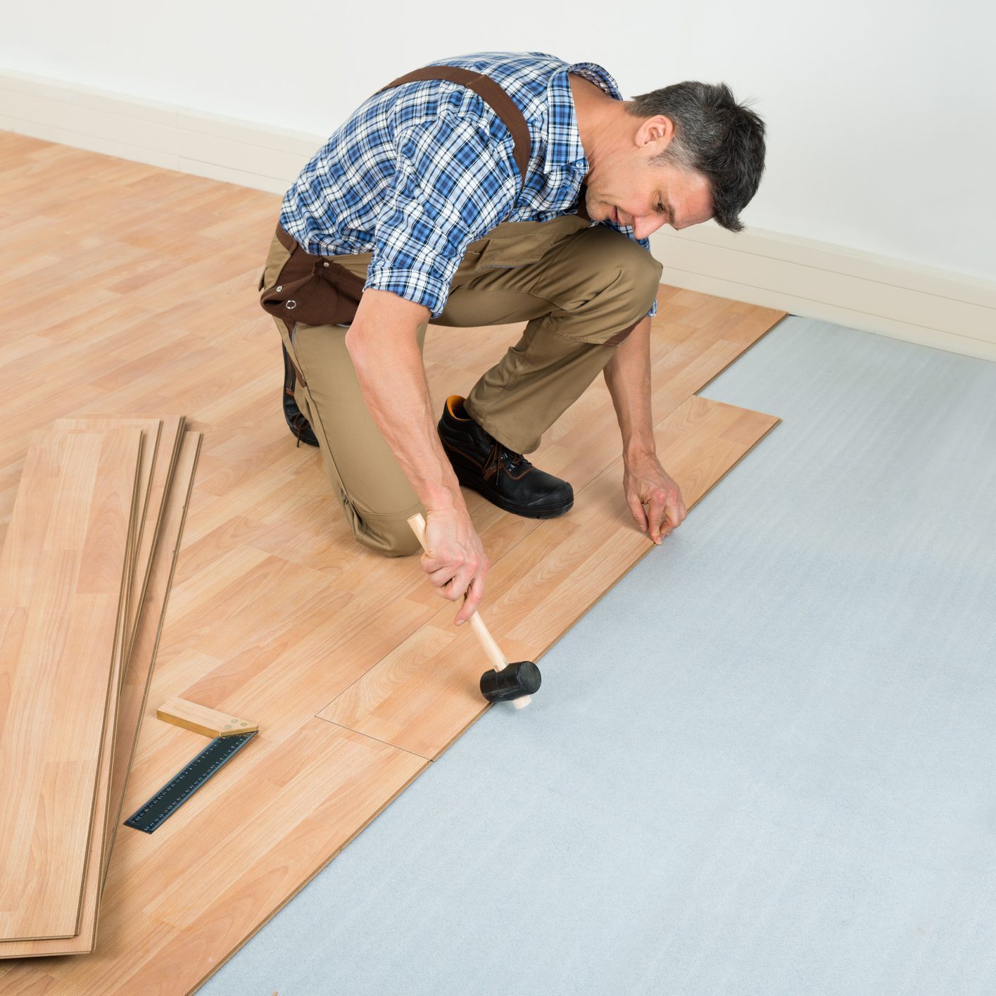 Carpenter Installing New Laminated Wooden Floor At Home